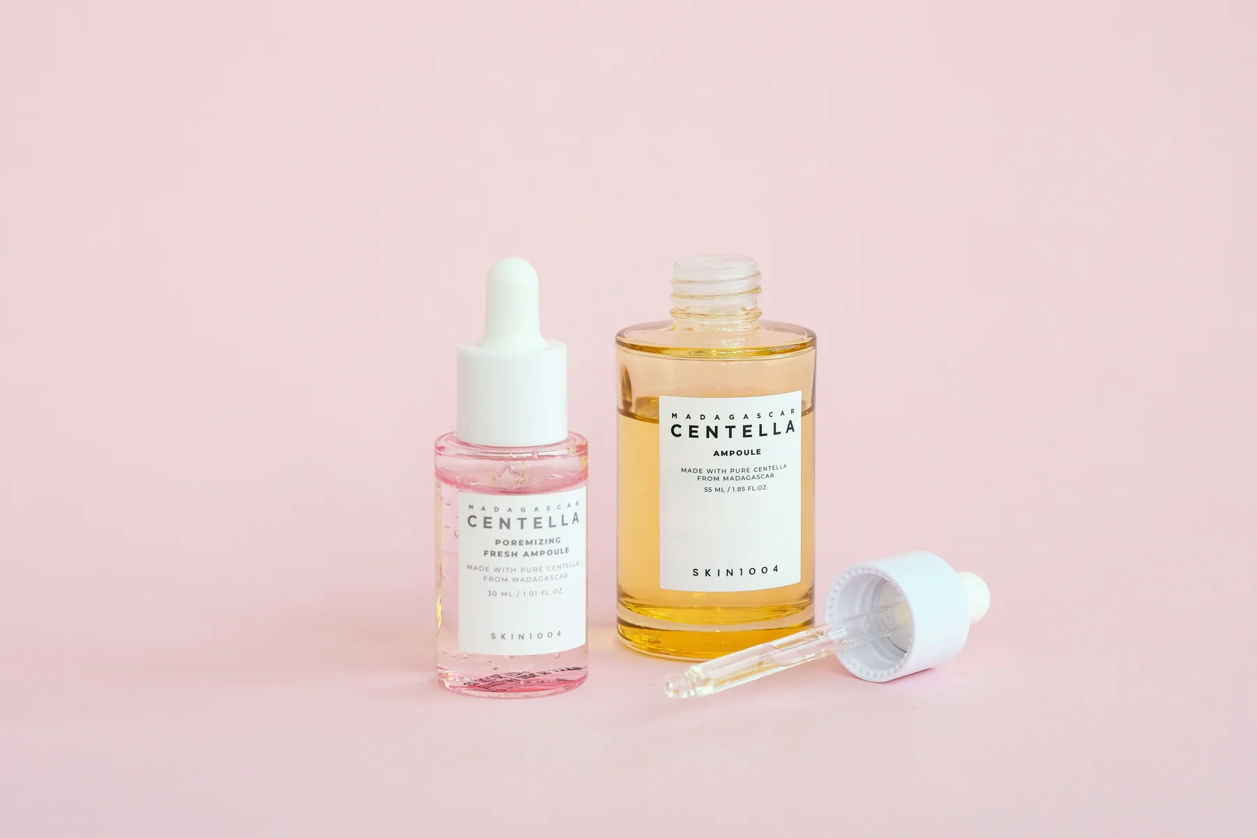 Skincare serums on a soft pink background