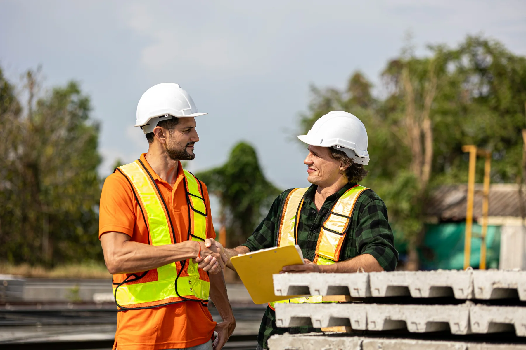 Two construction professionals shaking hands on site